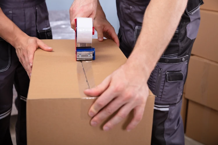Close-up of Denver movers sealing a moving box with tape—illustrating the benefits of a full packing service.