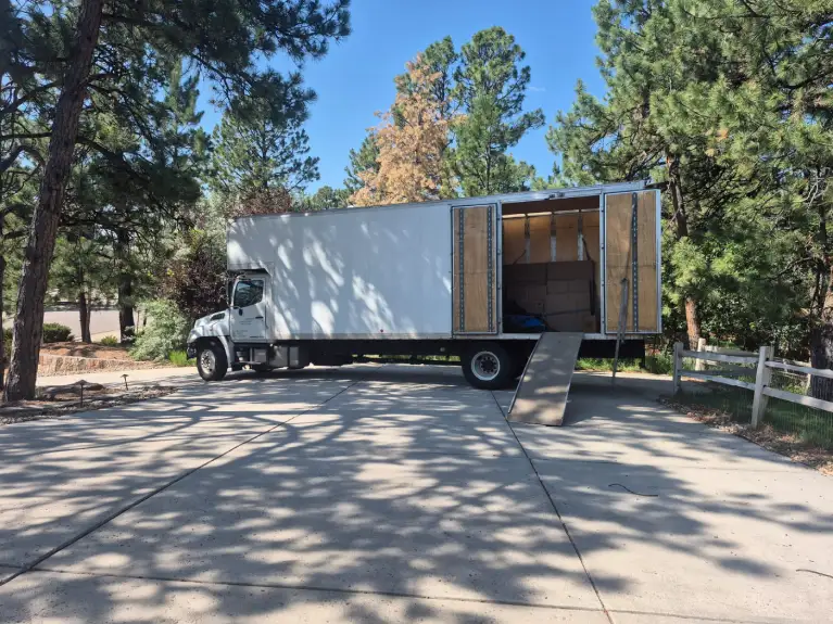 Moving truck parked in a Denver driveway with boxes inside, illustrating affordable local moving services and cost-saving strategies.