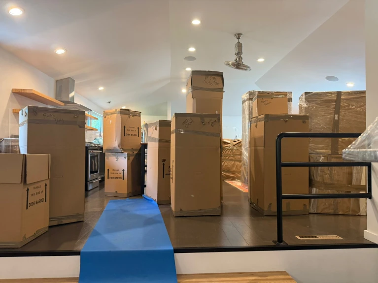 Stacked moving boxes in a Denver home with protective floor covering, showing smart packing to save costs during a local move.